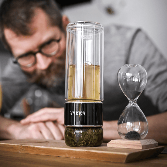 Mand ser på Vakka te brygger med oolong te i ved siden af et timeglas